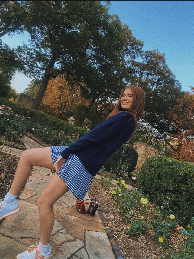 Kate Broderick in a garden, smiling over her shoulder.